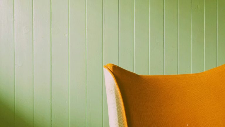 a yellow chair against a green wall in a room