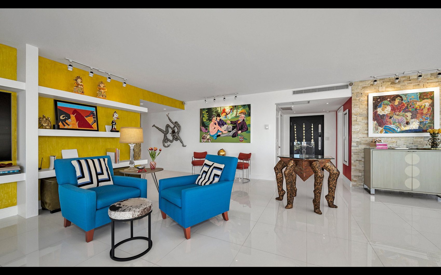 Diane's living room with bright blue armchairs, a yellow feature wall, and her art collection