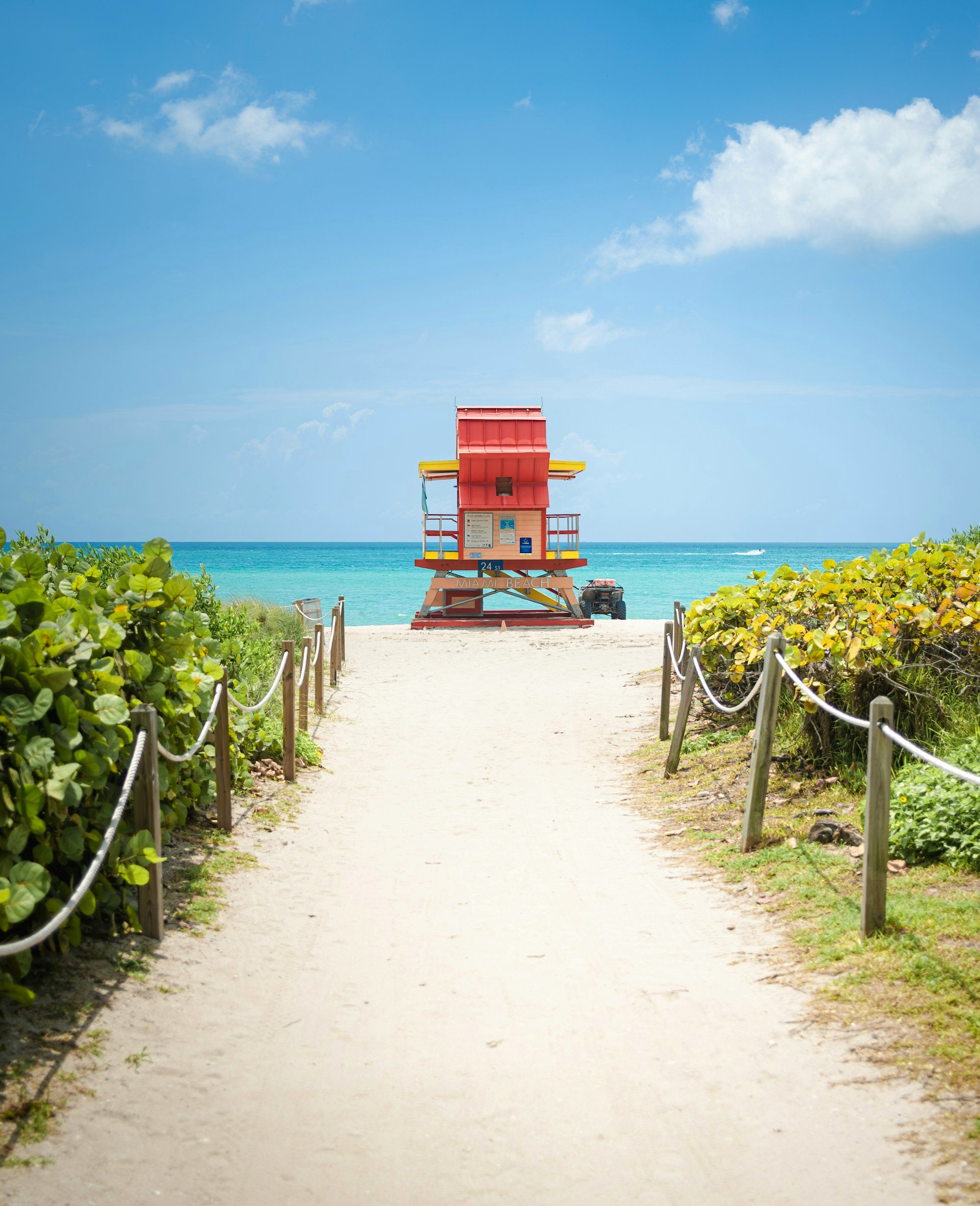 A sandy path leading to a red lifeguard tower on Miami Beach
