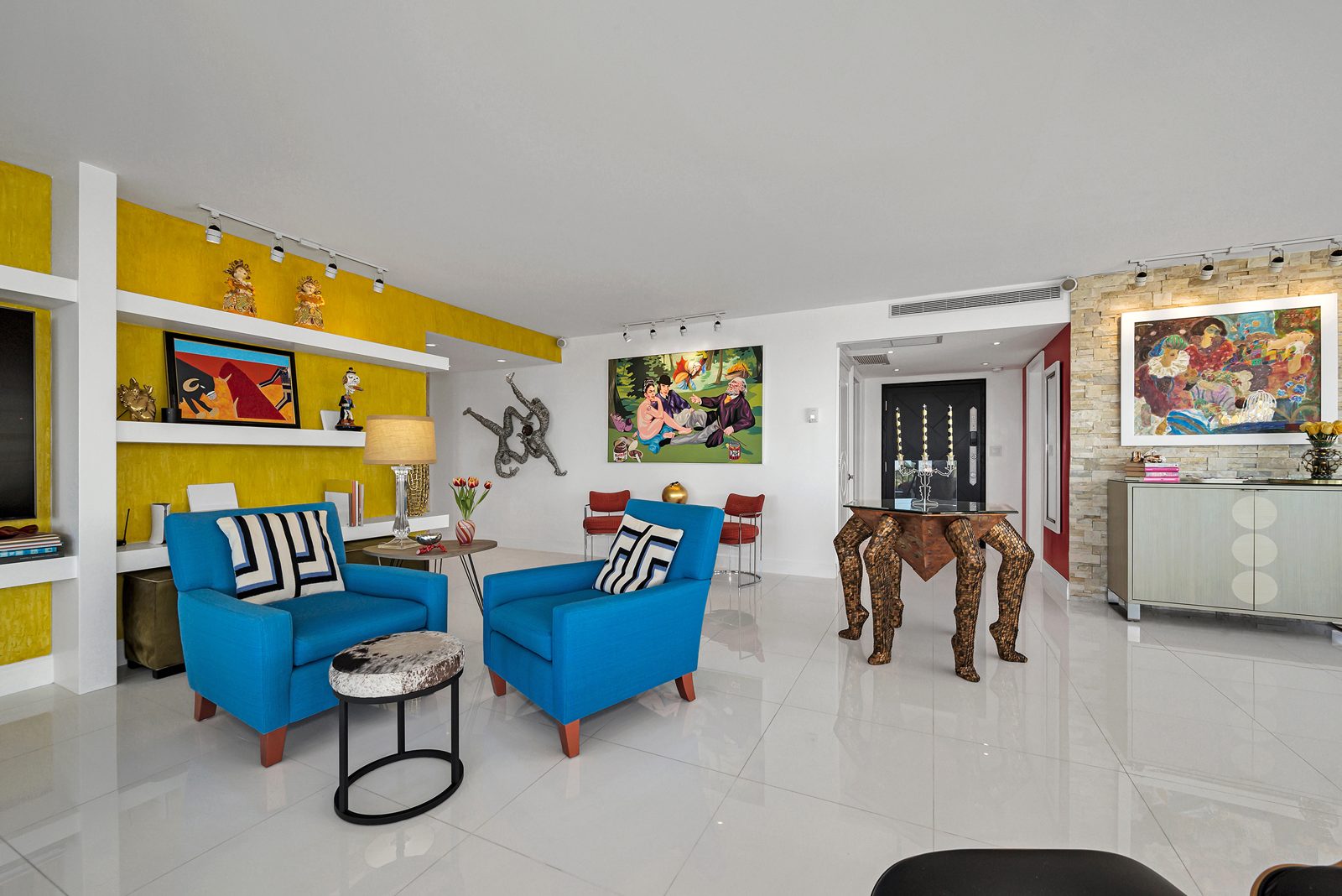 Diane's living room with a deep yellow feature wall and bright blue armchairs
