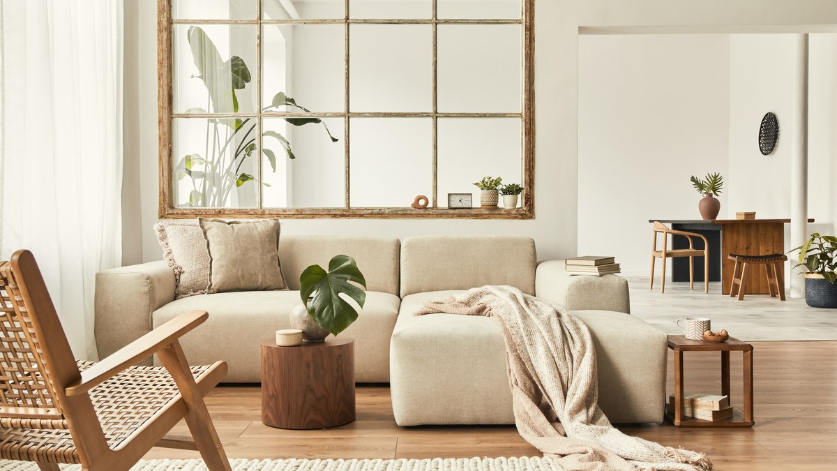 A styled cream living room with a modular sofa, rattan lounge chair and layered textures
