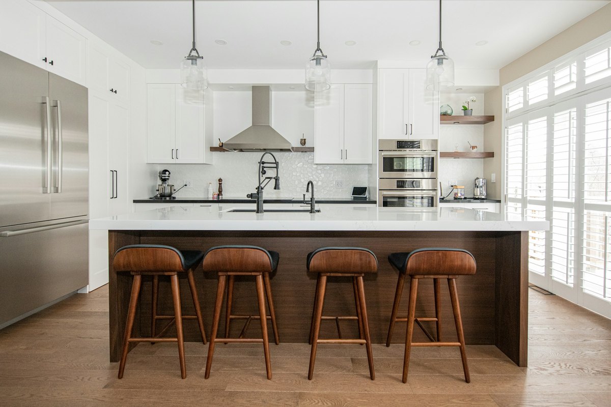 A bright modern kitchen with an island, stainless appliances and wooden bar stools