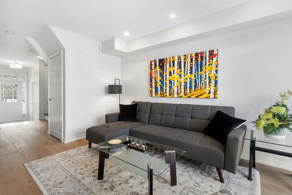 A bold colorful abstract painting above a gray sofa in a neutral room