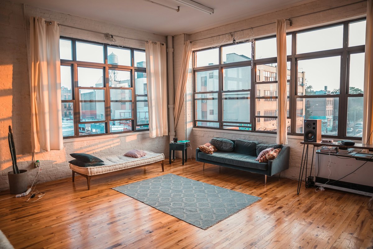 Sunlight pouring through a wall of tall windows in a bright living room