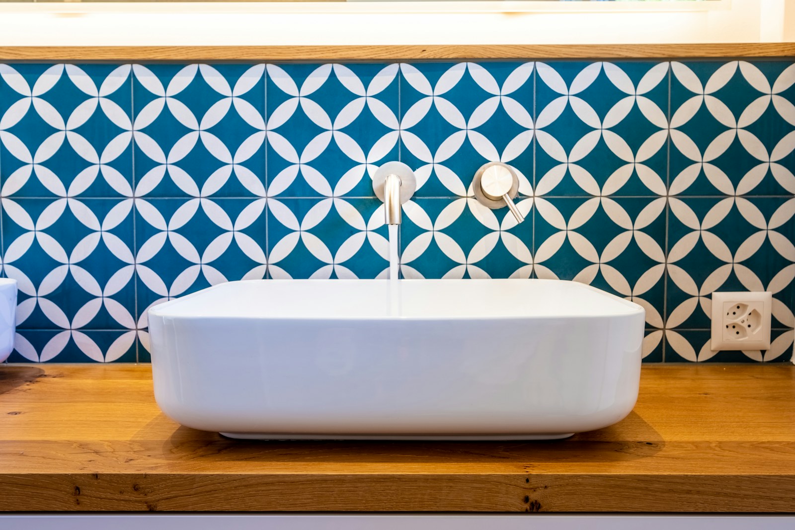 White bathtub against a wall of bold blue and white patterned tiles