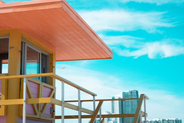 Coral and orange beach house with a wooden deck under a bright blue sky