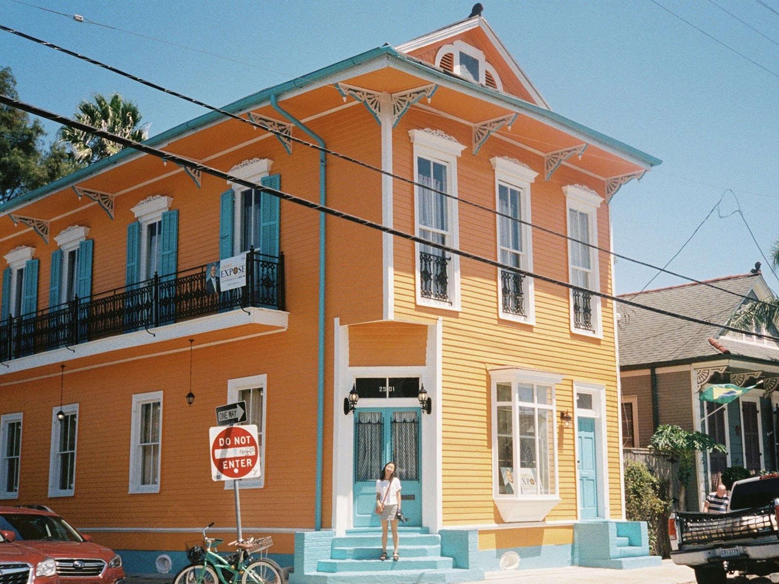 Orange two-story house with turquoise shutters and a balcony on a sunny corner