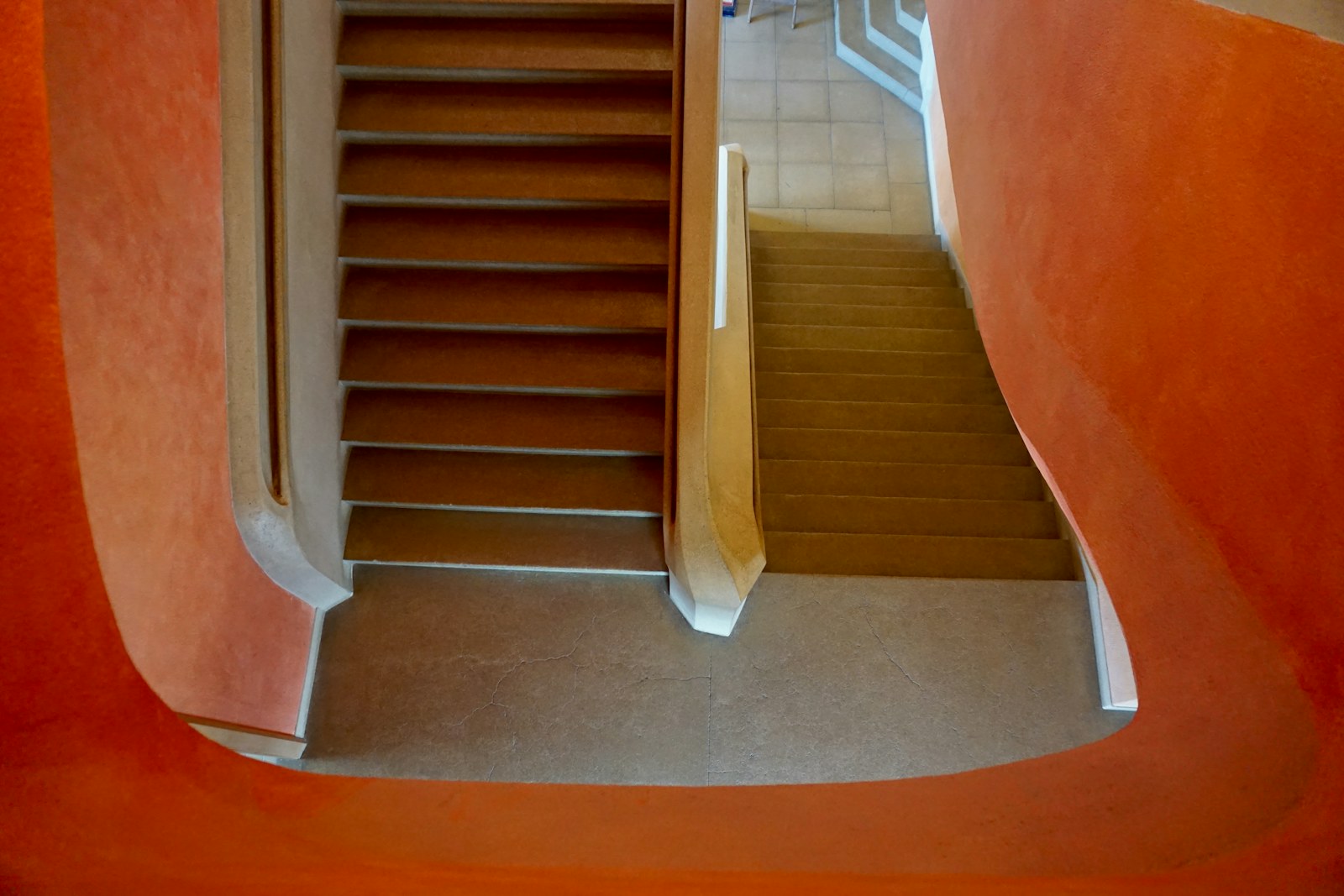 Wooden staircase inside a bold orange stairwell